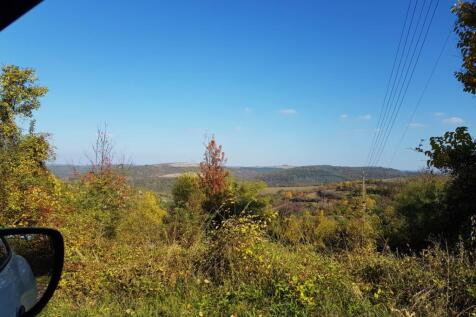 Scenic view of countryside hills and trees under a clear blue sky