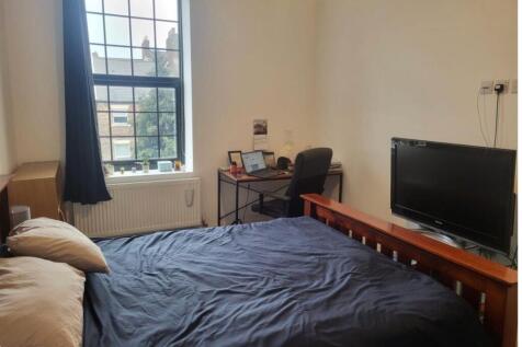 Bright bedroom with bed, desk and TV...