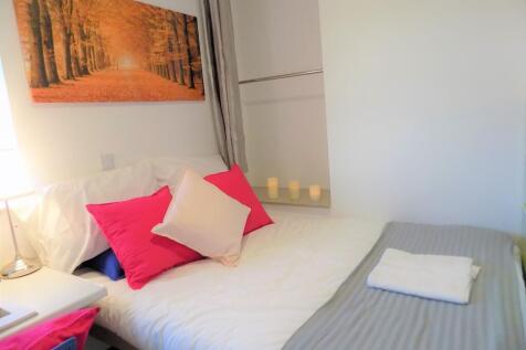Bright, neatly made bedroom with crisp white be...
