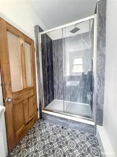 Modern walk-in shower with stylish patterned fl...