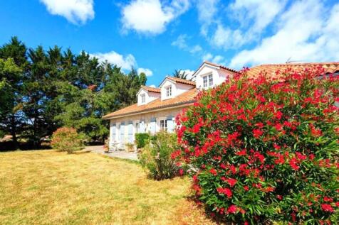 Une maison avec un toit en tuiles entourée de verd