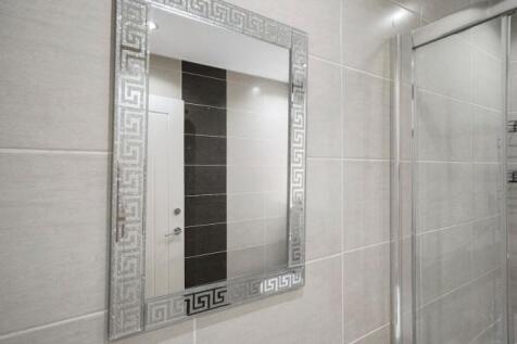 Elegant tiled bathroom with decorative mirror...