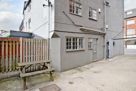 Shared rear yard with a wooden picnic bench, ga...