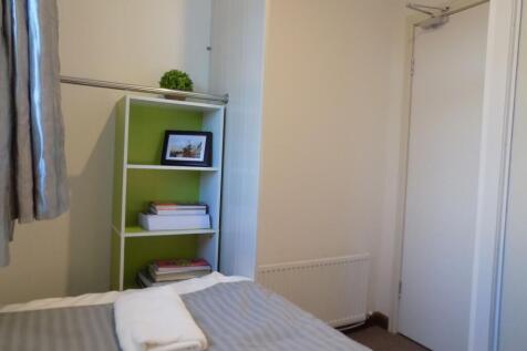 Neat single bedroom with a made bed, compact sh...