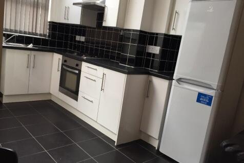 Modern kitchen with sleek black tiling and frid...