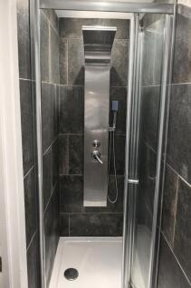 Modern tiled shower enclosure with sleek stainl...