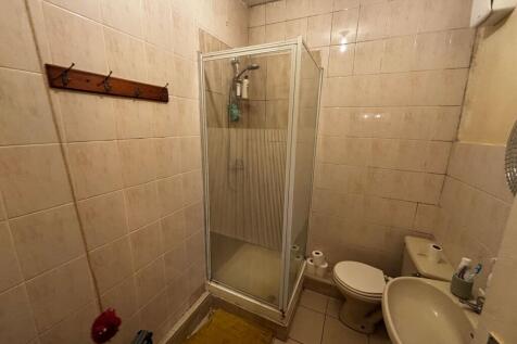Compact tiled bathroom with a corner shower cub...