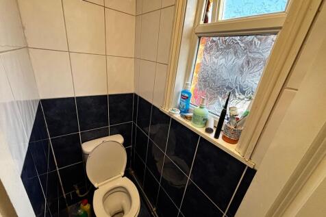 Compact tiled WC with a white toilet, frosted w...