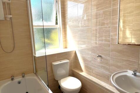 Bright, modern bathroom with tiled walls, a com...