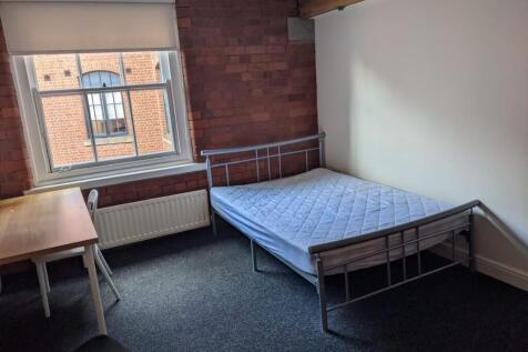 Bright bedroom with exposed brick feature wall,...