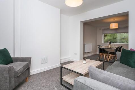 Bright, modern living room with grey sofas, a c...