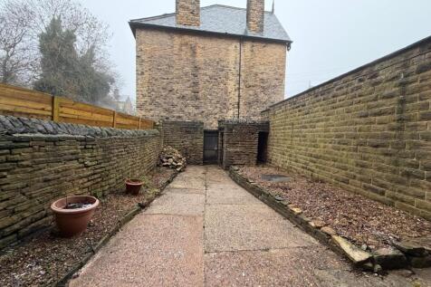 Private walled yard with paved pathway, raised ...