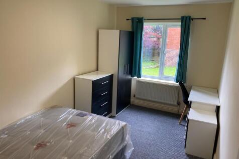 A well-lit, tidy single bedroom featuring a bed...