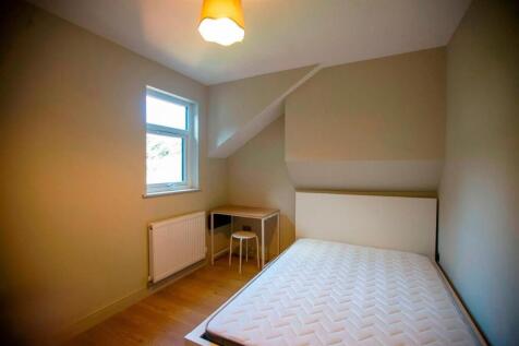 Compact bedroom with bed and desk near window...