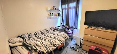 Cozy bedroom with bed, desk, and large TV...