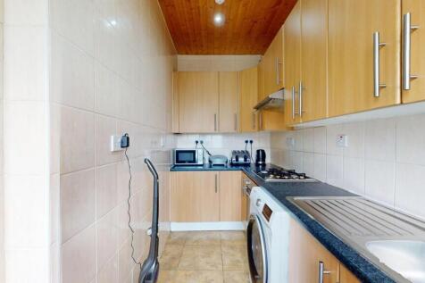 Well-equipped galley kitchen with light wood ca...