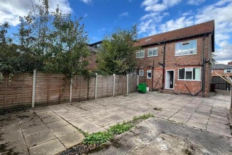 Paved rear outdoor space with mature trees, sec...