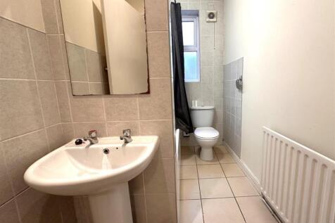 Bright tiled bathroom with a pedestal sink, mir...