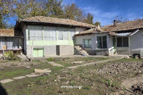 Back of the Bulgarian house featuring an enclosed porch with large windows and stone steps leading to the yard