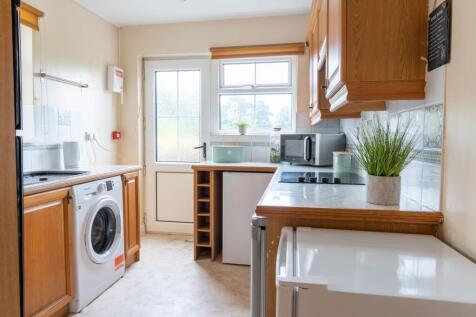Bright, neatly arranged kitchen with wooden cab...