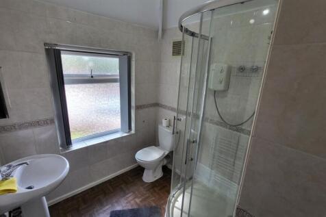 Bright modern bathroom with a corner glass show...