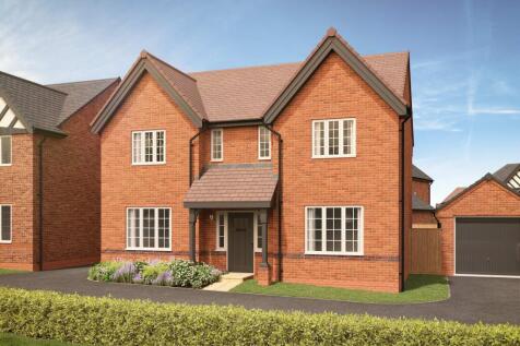 A red brick house with white-trimmed windows and a dark garage door sits behind a manicured hedge un