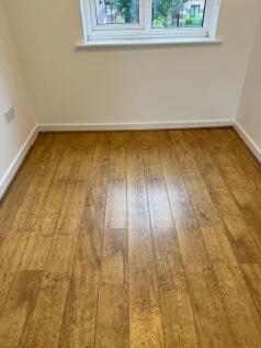 Bright room with warm wood-effect flooring and ...