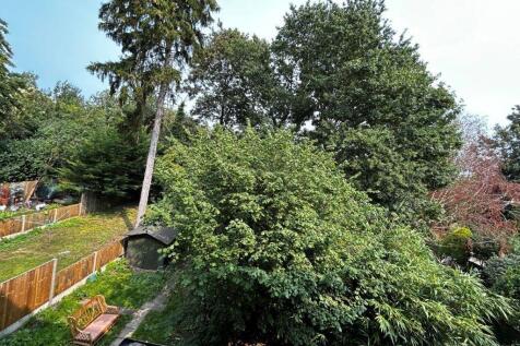 Lush private garden with mature trees and seati...