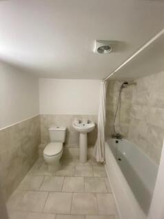 Bright, clean tiled bathroom with a full-size b...
