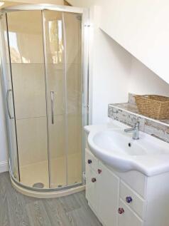 Bright, well-kept bathroom with a curved glass ...
