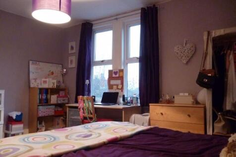 A cozy bedroom featuring a neatly made bed, a w...