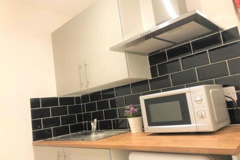A modern kitchen featuring sleek black tiled ba...