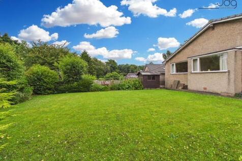 A generous lawned garden with mature planted borders and patio seating areas