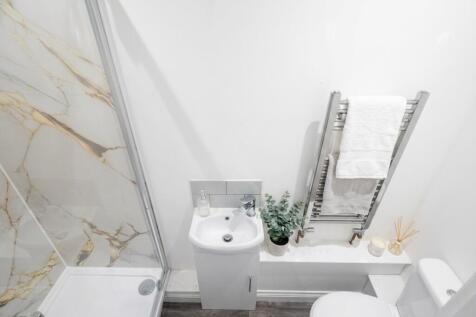Modern bathroom with marble tiling and towel ra...