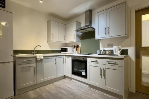 A bright and modern kitchenette with ample stor...