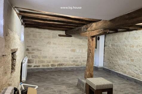Basement room showing exposed wooden beams and radiator on stone wall