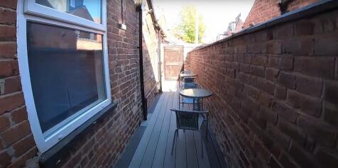 Narrow outdoor terrace with seating and brickwa...