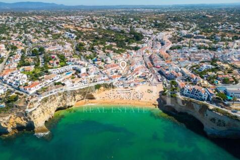 Aerial drone view of Carvoeiro beach in Algarve with turquoise water and cliffs near the property.