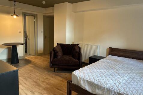 Spacious bedroom with stylish wooden flooring a...