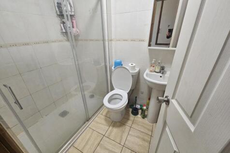 Compact, clean bathroom with a glass-enclosed w...