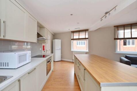 Bright modern kitchen with white cabinetry, a l...