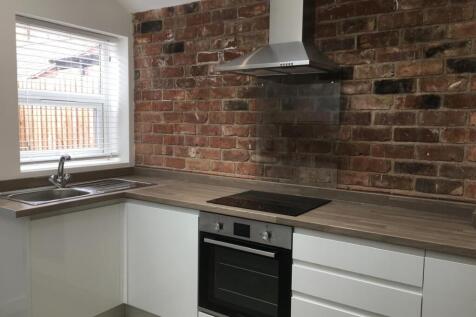 Modern fitted kitchen with white cabinetry, woo...