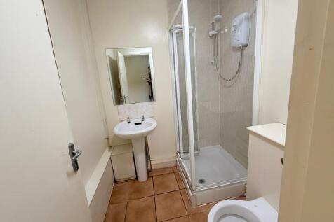 A compact bathroom featuring a shower enclosure...