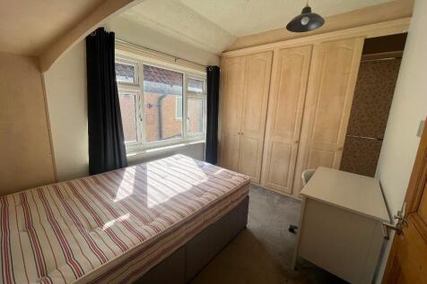 Bright single bedroom with a large window letti...