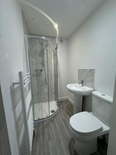 A modern bathroom featuring a curved glass show...