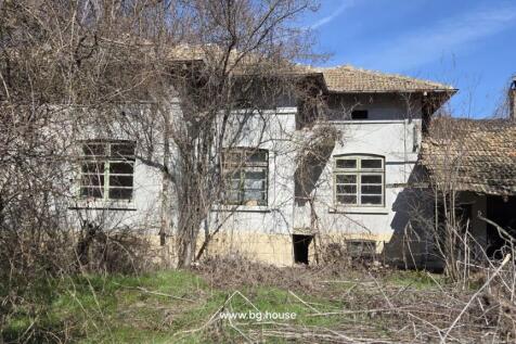 Exterior view of an old house showing three windows and leafless trees in front during winter
