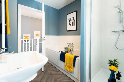 A modern bathroom with a white bathtub, blue walls, and a framed artwork on the wall