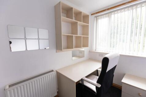 A bright and tidy bedroom featuring a clean des...