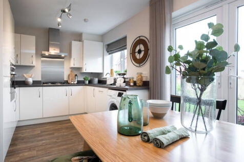 A modern, well-lit kitchen with white cabinets, wooden countertops