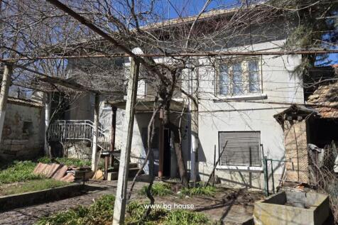 Front facade of the house with garden and vine-covered trellis in early spring